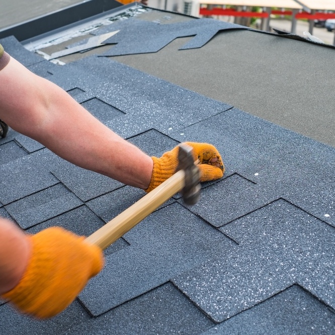 A roofer is hammering nails into a new roof system.