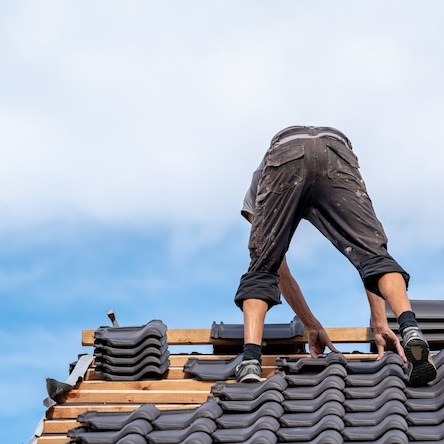 roofer adjusting tiles on the slope of a residential roof system