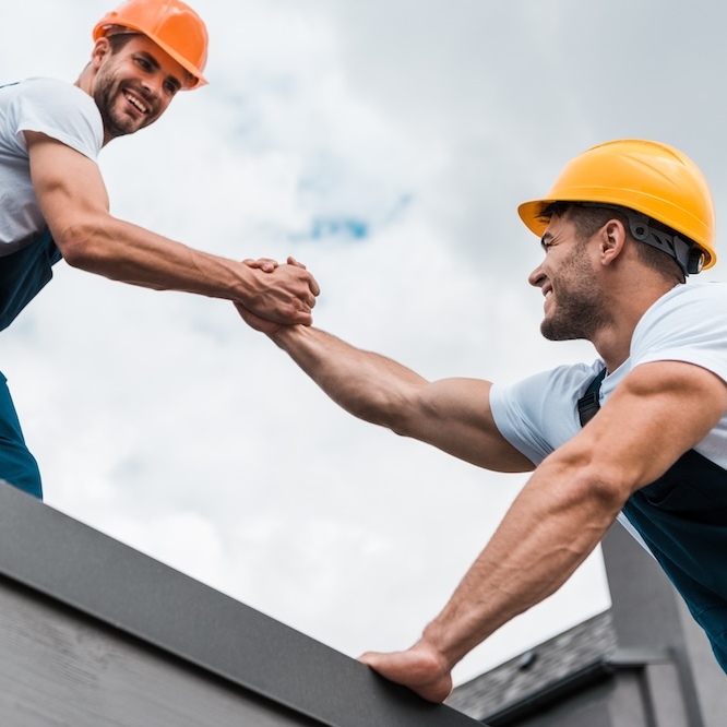 Two roofers helping one another.